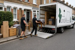 Removal staff load reusable furniture into a white removals lorry during a house clearance.